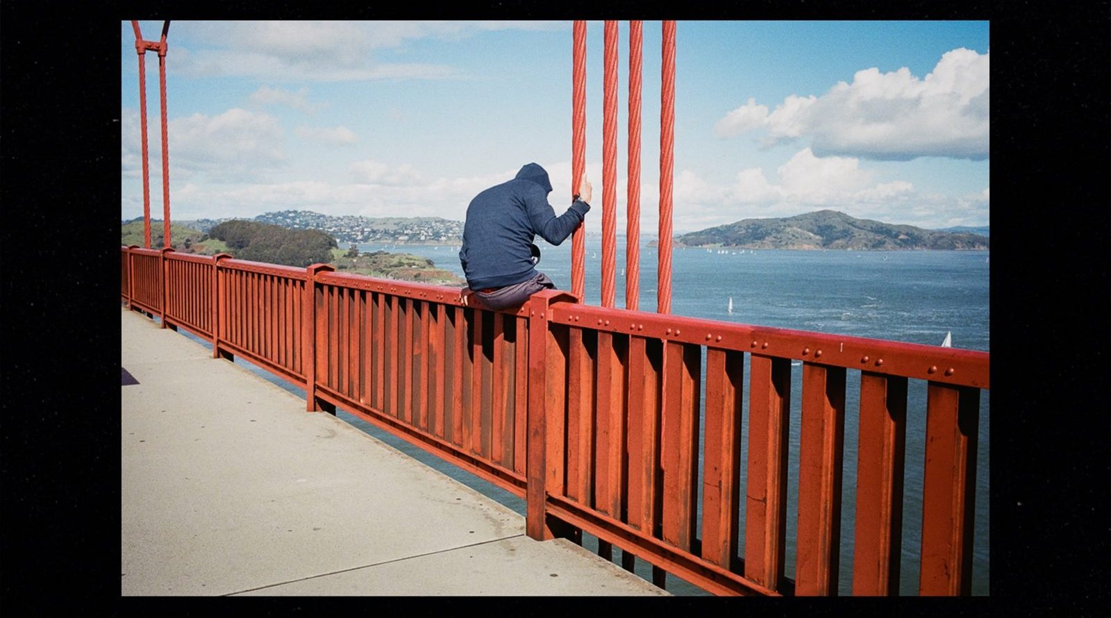 a man sitting on the Golden Gate Bridge railing
